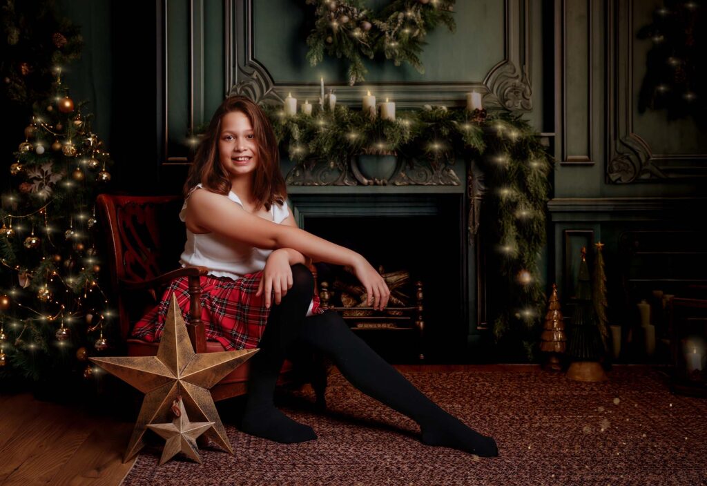 Girl sitting by the cosy Christmas fireplace set at Annie Griggs Photography, St Albans