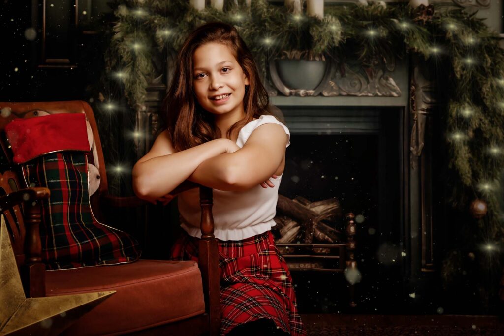 Smiling girl leaning on a vintage chair beside the Christmas fireplace